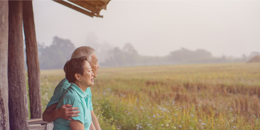 an elderly couple looking toward a farm field wistfully